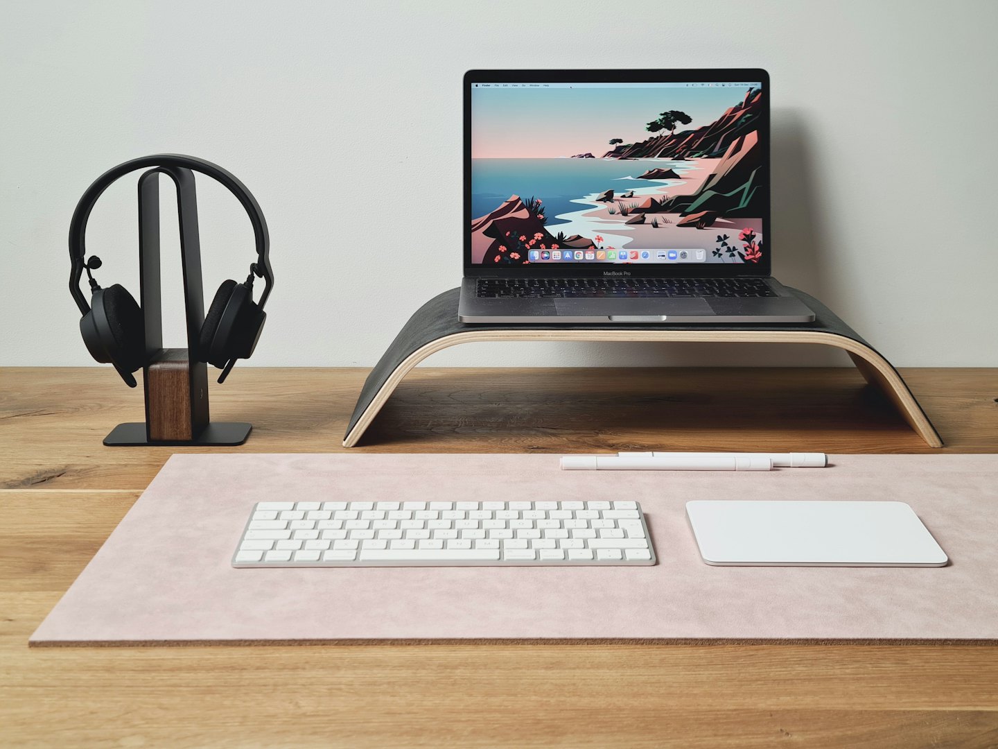 Laptop, cuffie, tastiera e trackpad su una scrivania.