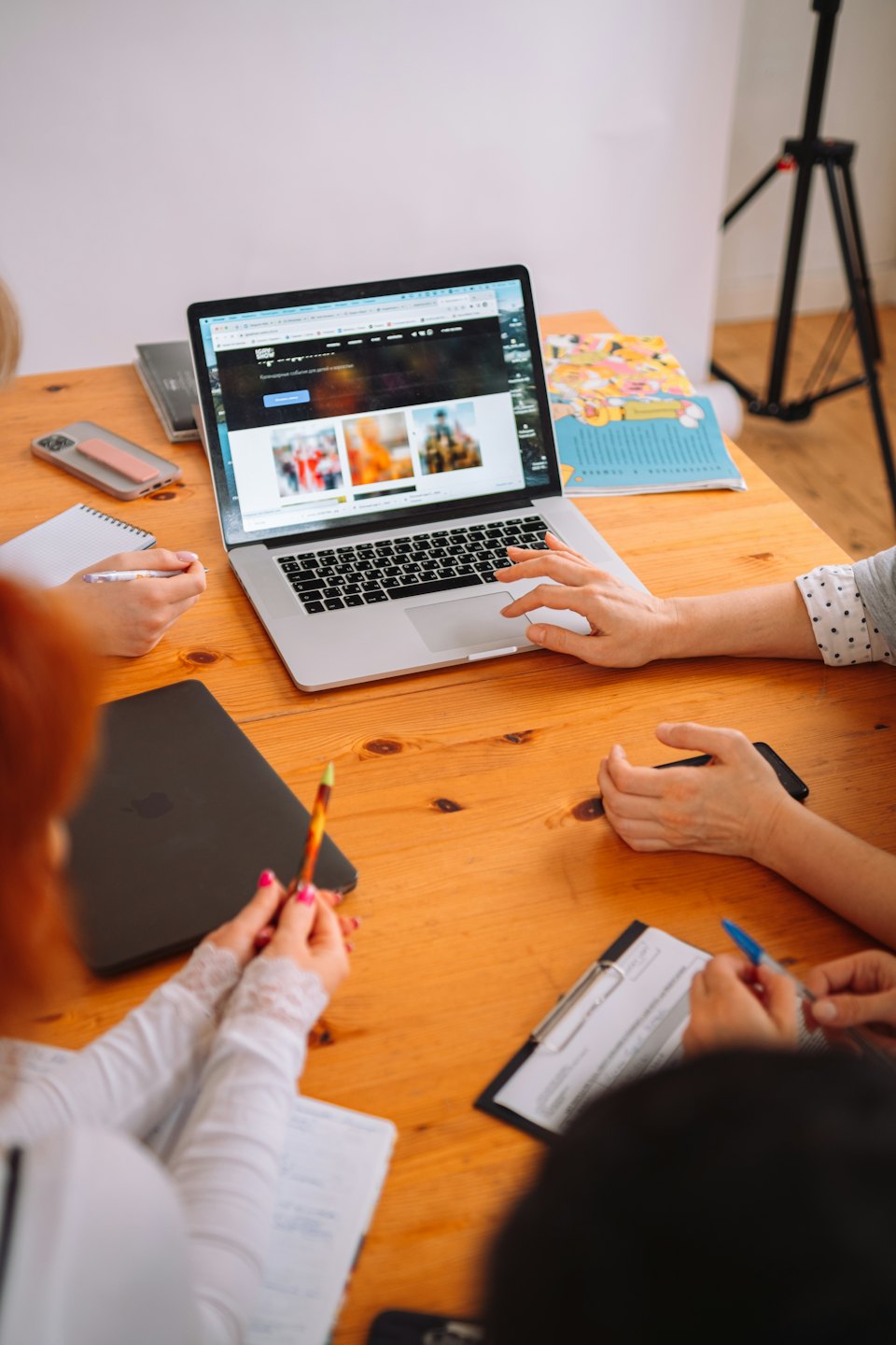 Un team collabora attorno a un tavolo con un laptop e quaderni.